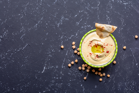 Healthy food. Vegetable sources of protein. Bowl of hummus, on black stone table, chickpeas.の写真素材