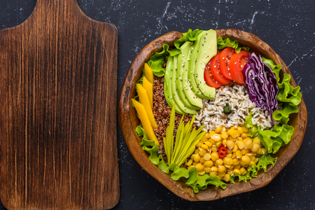 Healthy vegan superfood bowl with quinoa, wild rice, chickpea, tomatoes, avocado, greens, cabbage, lettuce on black stone background top view with copy space.の写真素材