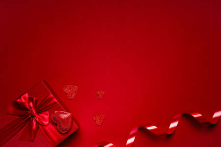 Red box with ribbon, with hearts on a red background with copy space. Valentine's Day gift,...