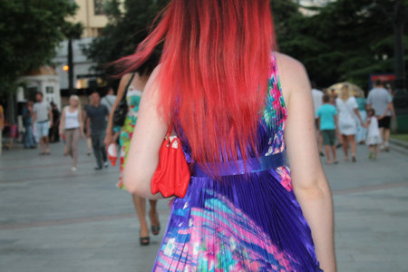 girl, evening walk, beautiful hair color, amber, sleeveless dress, red handbag under the armpit, summerの写真素材
