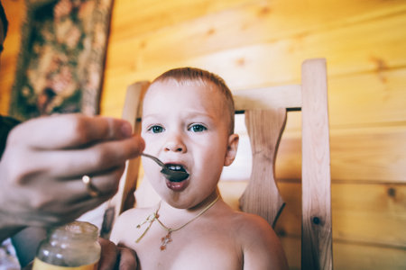 Mom feeds baby sitting in chairの写真素材