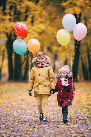 brother and sister playing with balloons in an autumn parkの写真素材
