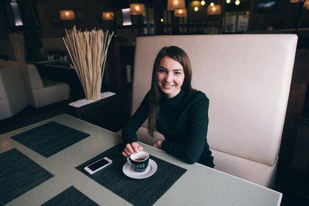 A beautiful business lady in a black shirt smiling in a cafeの写真素材
