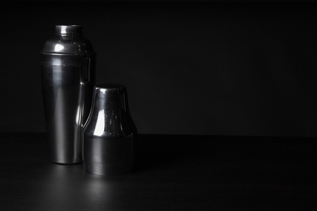 Barman equipment. Shaker on a wooden table with black background. Space for text.の写真素材