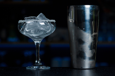 A chilled shaker and a glass Chalet with a sugar border full of ice is on the bar counter with a blurred bar  backgroundの写真素材