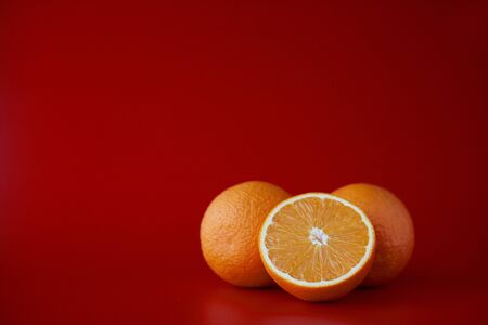 orange fruit and half cut orange on red backgroundの写真素材