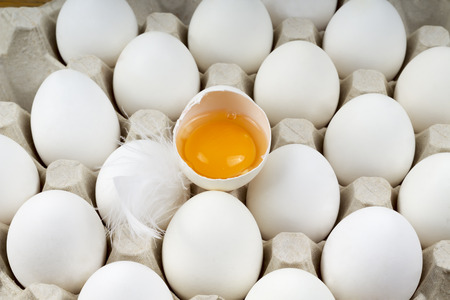 a large tray with eggs and one brokenの写真素材