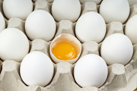 a large tray with eggs and one brokenの写真素材
