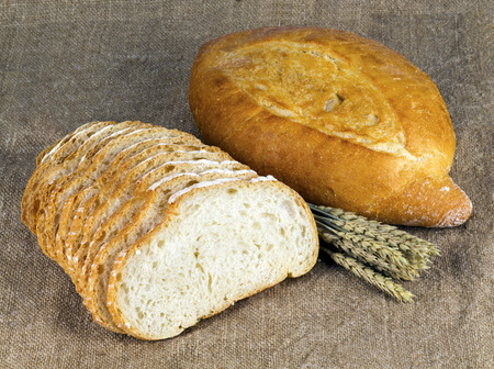 Bread on burlap with wheat spikeletsの写真素材