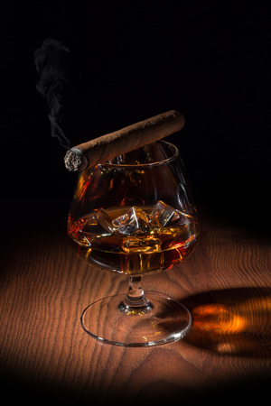 cigar smoking on a glass in which ice and cognacの写真素材