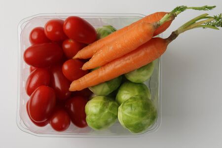 Brussels sprouts, carrot and cherry tomato in plastic box top viewの写真素材