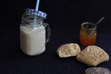 Buns with seeds, jam and milk in a jar, breakfast.の写真素材