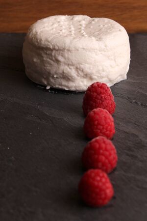 cottage cheese quark cheese with raspberry on a stone slate board.の写真素材