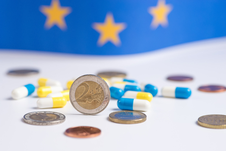 Yellow and blue pills with coins on a blue background. Euro coins. Copy space for textの写真素材