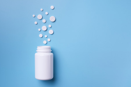 Assorted pharmaceutical medicine pills, tablets and bottle on blue background. Copy space for text