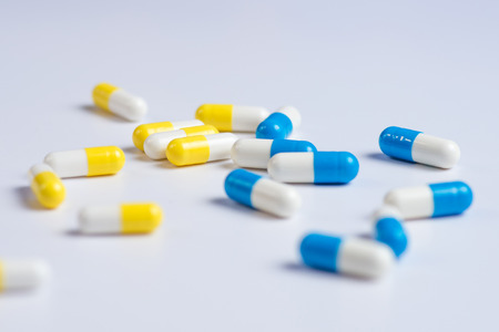 Yellow and blue pills or capsules on a white background with copy space.
