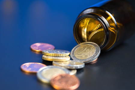 Coins in a glass bottle on a back backgroundの写真素材
