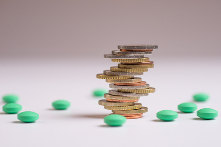 Coins are placed among themselves in different positions next to the green pills. Copy space for textの写真素材