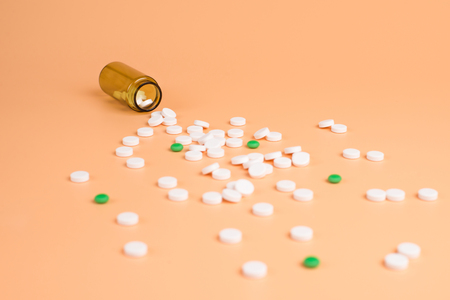 White and green pills in the brown glass bottle on a orange background. Copy space for textの写真素材