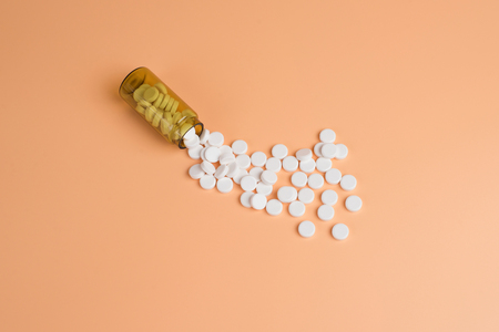 White pills in the brown glass bottle on a orange background. Copy space for textの写真素材