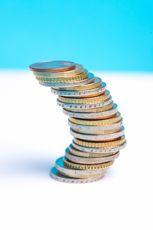 Coins stacked on each other in different positions on a blue and white background. Copy space for textの写真素材
