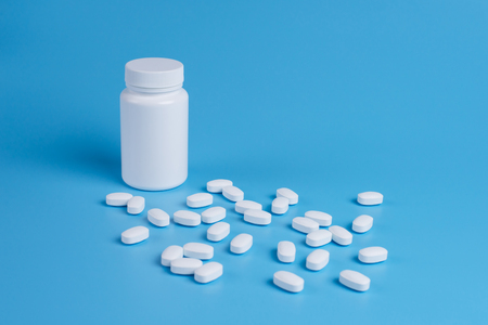 White pills, tablets and white bottle on blue background. Copy space for textの写真素材