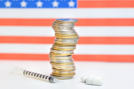 Coins stacked on each other in different positions on colored background. US economy. Pharmaceutical industry in US.の写真素材