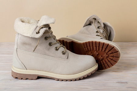 Bright leather winter boots on a light wooden background.