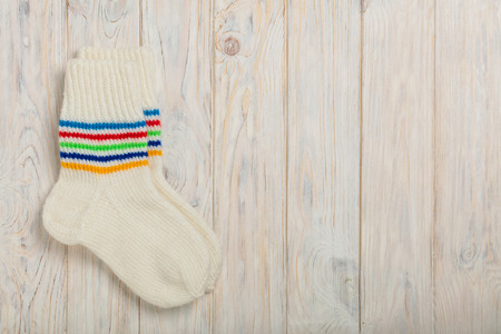 Knitted wool socks white color on light wooden background.の写真素材