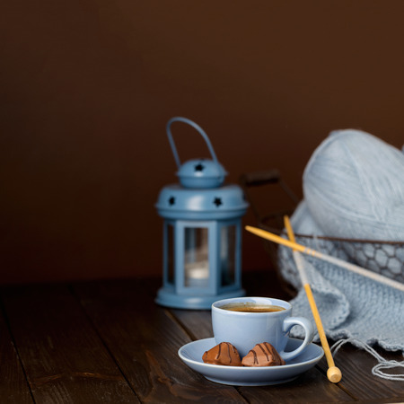 Knitting from light blue yarn. Cup of coffee and chocolates.の写真素材