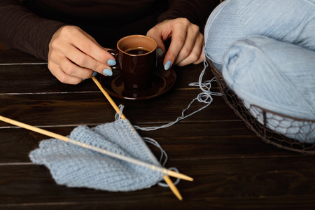 Female hands, cup of coffee. Knitting from light blue yarn.の写真素材