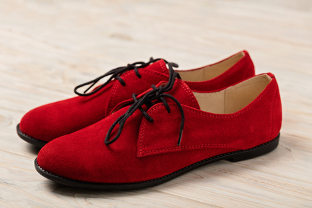 Red women's shoes oxfords on a light wooden background. Selective focus.の写真素材
