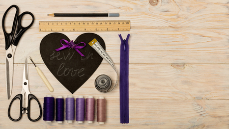 Sewing accessories of purple color and heart with an inscription - sew in love. Selective focus.