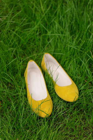 Yellow female shoes on green grass. Blurred macro photo. Selective focus.の写真素材