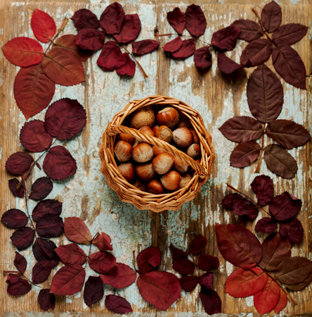 Flat lay frame of autumn crimson leaves with basket walnuts on a blue wooden background. Selective focus.の写真素材