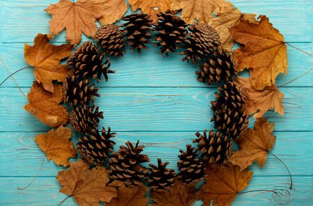 Flat lay frame of autumn leaves, cones on a wooden background of azure color. Selective focus.の写真素材