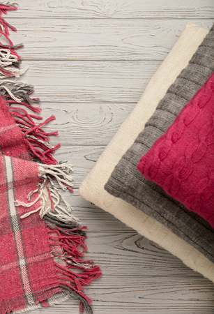 Knitted pillows and plaid on a light wooden background. Top view. Flat lay.の写真素材
