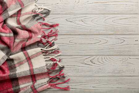 Plaid on a light wooden background. Top view. Flat lay.