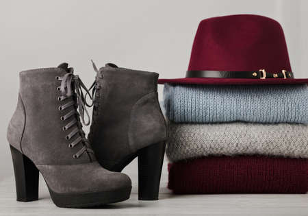 Pile of knitted clothes (sweaters, scarves, pullovers) blue, burgundy, gray colors, shoes and hat. Selective focus.の写真素材