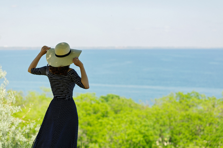 Young woman in a long dark blue skirt on the waterfront near the sea. Selective focus.の写真素材