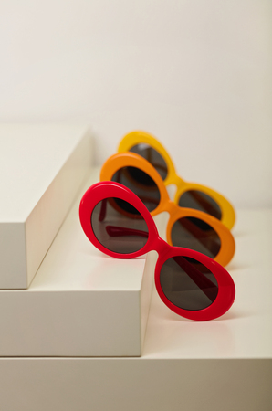 Sunglasses of red, orange and yellow colors on a white background. Selective focus.の写真素材