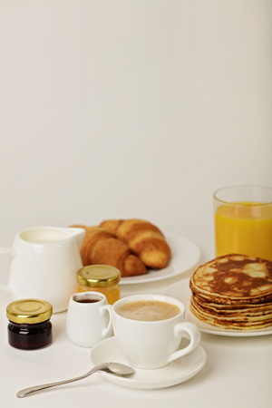 Breakfast - coffee with croissants, juice with pancakes on a white background. Selective focus.の写真素材