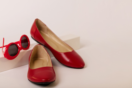 Female accessories of red color - shoes and sunglasses on a white background. Selective focus.の写真素材