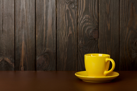 Ceramic cup for coffee and tea of yellow color on a dark wooden background. Selective focus.の写真素材