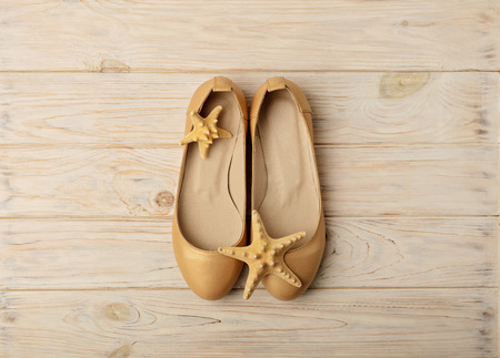 Fashion trend - women's shoes golden pearl color on a wooden background. Selective focus.の写真素材