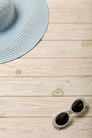 Beach summer concept. Blue female hat and sunglasses on a light wooden background. Selective focus.の写真素材