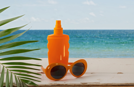 Summer seascape. Relax on the beach, sunblock, hat and orange sunglasses. Selective focus.の写真素材