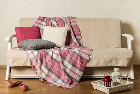 Beige sofa with plaid and colorful pillows (pink, grey, white) in the living room. Selective focus.の写真素材