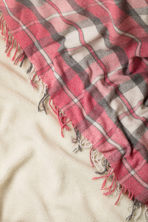 Winter time. A cozy warm pink blanket and a cup of coffee and croissants on the bed. Selective focus.の写真素材