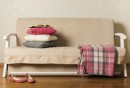 Beige sofa with plaid and colorful pillows (pink, grey, white) in the living room. Selective focus.の写真素材